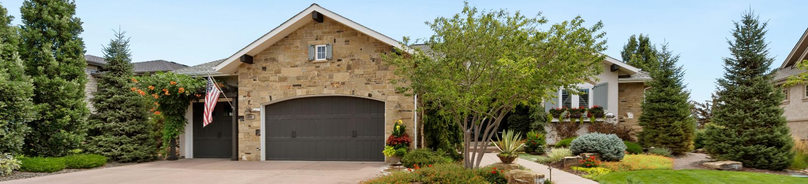 Front view of a single-story Fountain Valley home featuring a stone facade, manicured landscaping, and a modern, well-maintained garage door