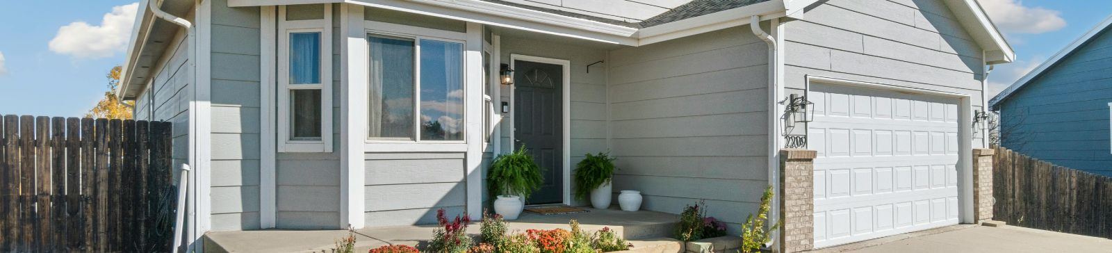 Front view of a modern Fountain Valley home with a clean, white garage door and landscaped entryway
