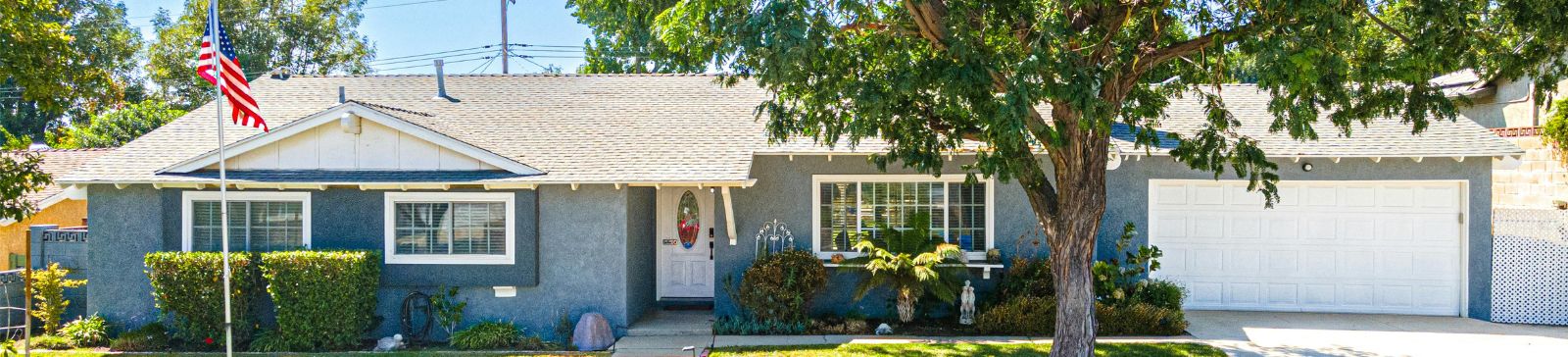 Single-story Fountain Valley home with a white, well-maintained garage door and lush landscaping