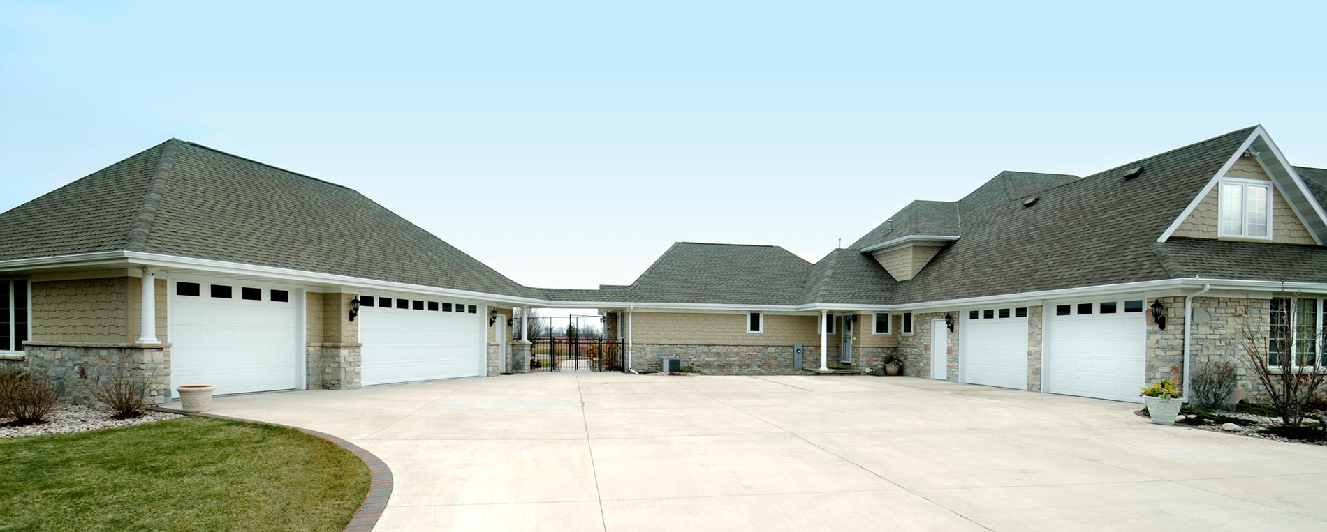 Large residential home featuring multiple modern garage doors with spacious driveway—Garage Door Repair Fountain Valley
