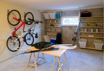 Organized garage featuring wall-mounted bike racks, open shelving, and a workbench with tools and sports equipment in Fountain Valley, CA