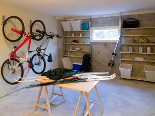 Custom Garage Organization with Wall-Mounted Racks and Shelving Organized garage featuring wall-mounted bike racks, open shelving, and a workbench with tools and sports equipment in Fountain Valley, CA