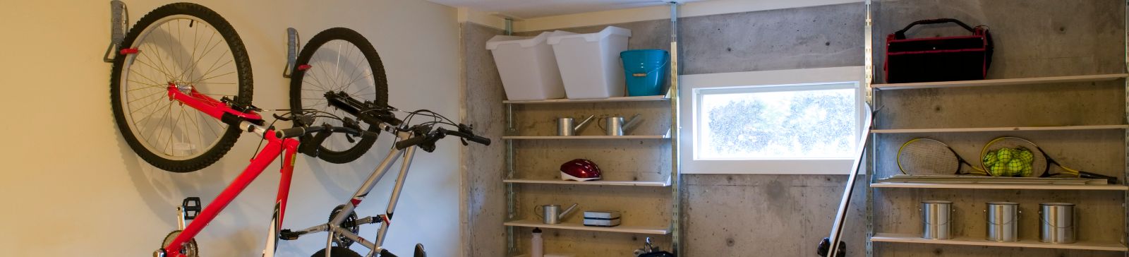 Organized garage featuring wall-mounted bike racks, open shelving, and a workbench with tools and sports equipment in Fountain Valley, CA