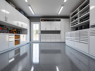 Spacious, modern garage featuring white custom cabinets, organized shelving, and a glossy epoxy floor—showcasing 2025 garage organization trends
