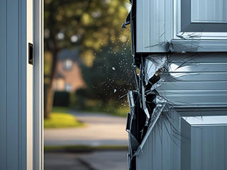 Close-up of a cracked and shattered garage door panel, highlighting the aftermath of a garage door accident in a residential neighborhood